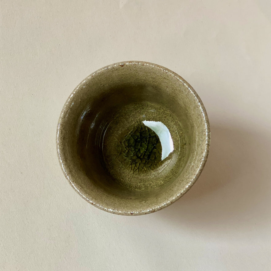 Blue Karatsu teacup with deep green glassy glaze and black iron speckles, viewed from the top down.
