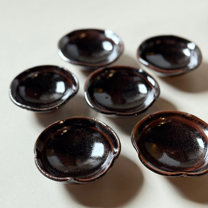 Black Karatsu flower-shaped small plates set of 6 with glossy black finish, perfect for serving seasonal appetizers.