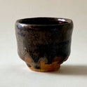Black Karatsu sake cup with glossy dark ash glaze and rustic brown base, handcrafted by Kimiyuki with a unique texture.