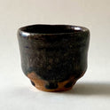Black Karatsu sake cup with moist black glaze and natural ash texture, diameter 6.5cm, height 5.5cm.
