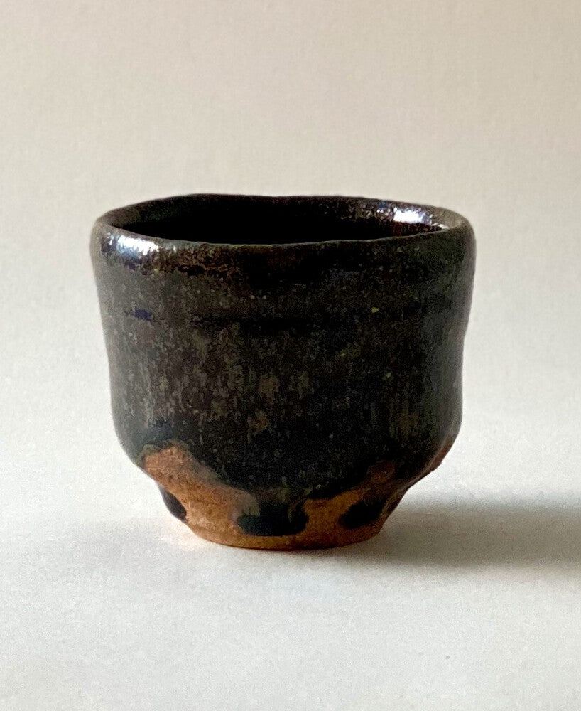 Black Karatsu sake cup with moist black glaze and natural ash texture, diameter 6.5cm, height 5.5cm.