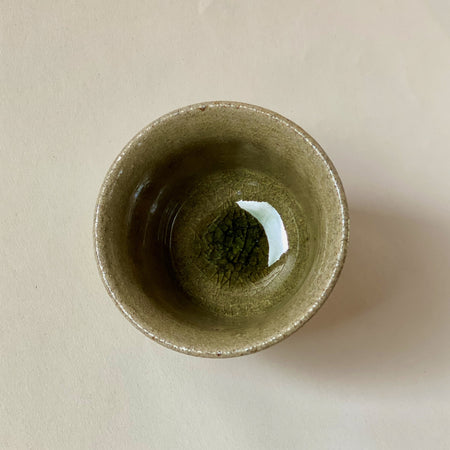 Blue Karatsu teacup with deep green glassy glaze and black iron speckles, viewed from the top down.