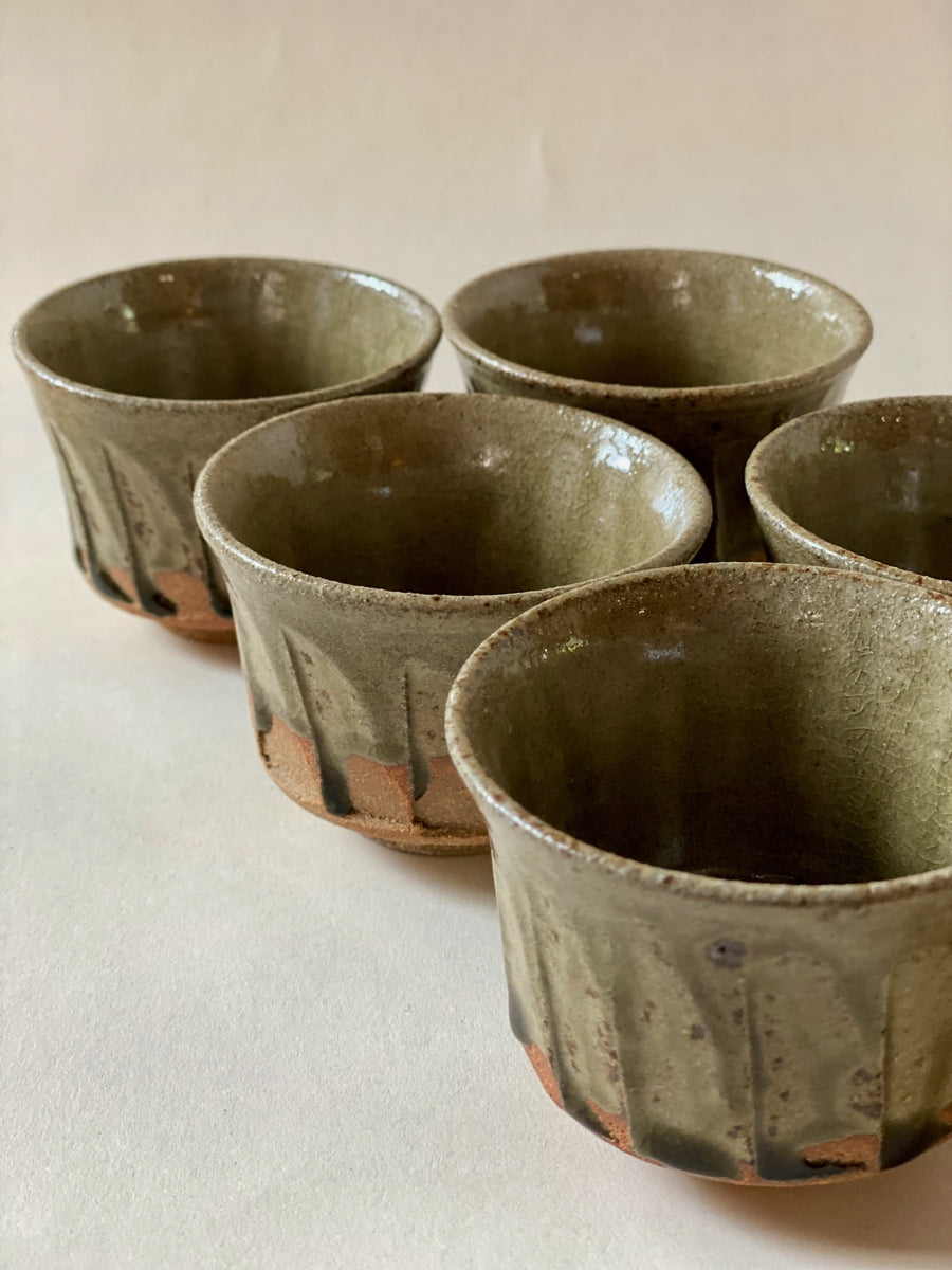 Blue Karatsu teacup set with deep green glaze and black iron dots on Karatsu ware clay surface.