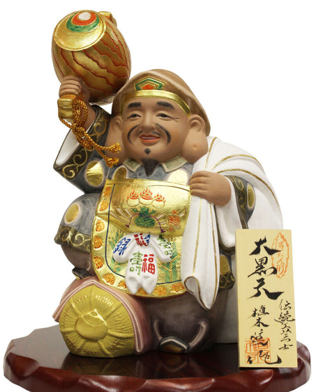 Daikokuten Hakata Doll by Susumu Ueki, 25cm tall, featuring gold and white traditional attire on wooden base.